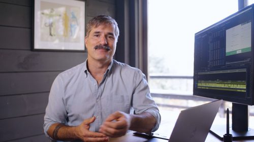 Nick sits at desk in front of computer with editing software open